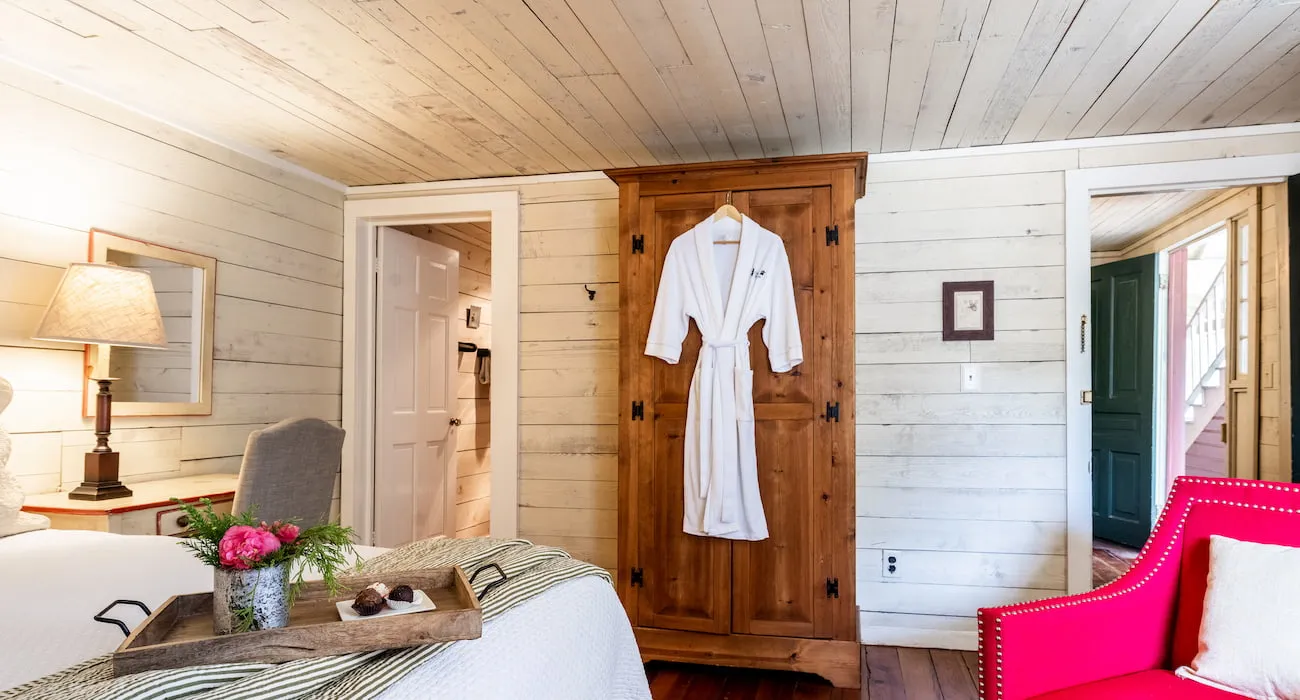 Tan wood guest room with robe on armoire